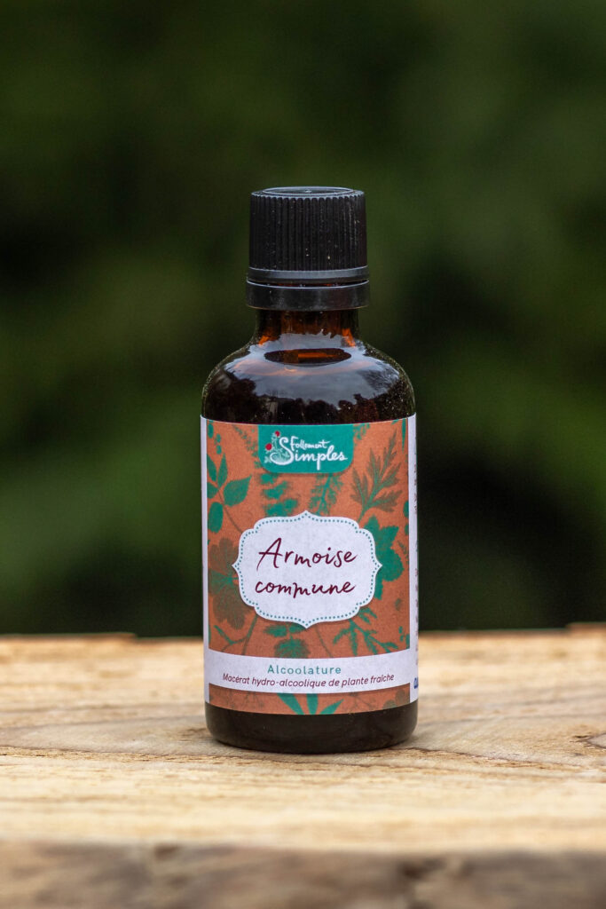 Un flacon d'alcoolature d'armoise commune posé sur une planche en bois